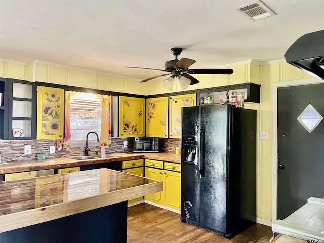 kitchen featuring ceiling fan, light hardwood / wood-style floors, black fridge, sink, and ornamental molding