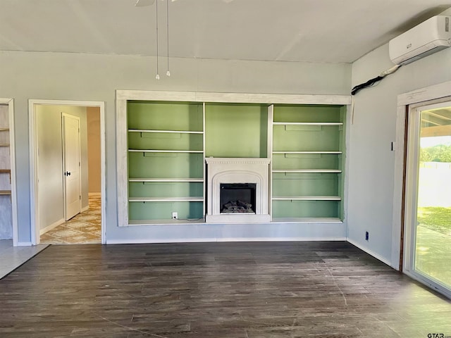 unfurnished living room featuring built in shelves, hardwood / wood-style flooring, and a wall unit AC