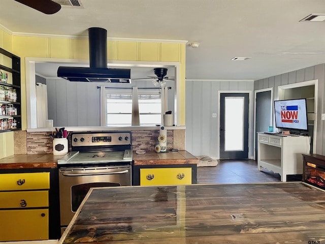 kitchen with island exhaust hood, stainless steel range with electric cooktop, a wealth of natural light, and ornamental molding