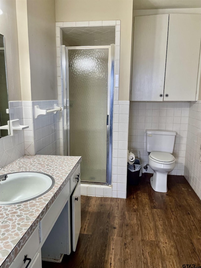 bathroom with tile walls, hardwood / wood-style flooring, vanity, and an enclosed shower