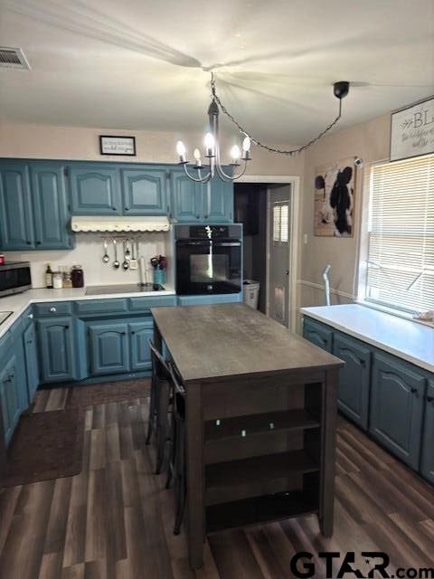 kitchen featuring dark wood finished floors, visible vents, black appliances, and blue cabinets