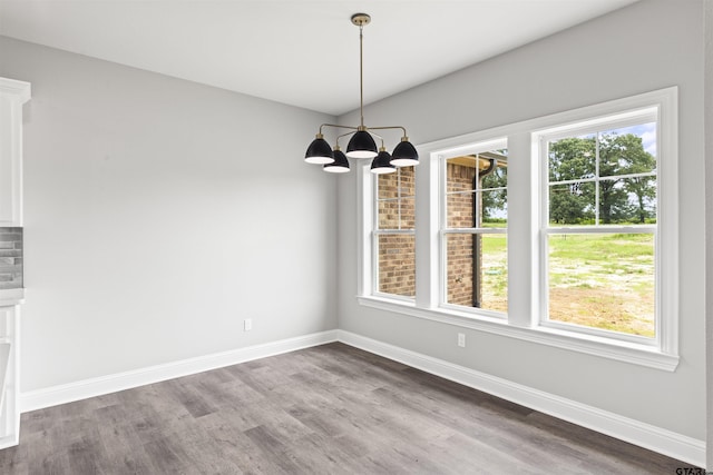 unfurnished dining area featuring an inviting chandelier and hardwood / wood-style flooring