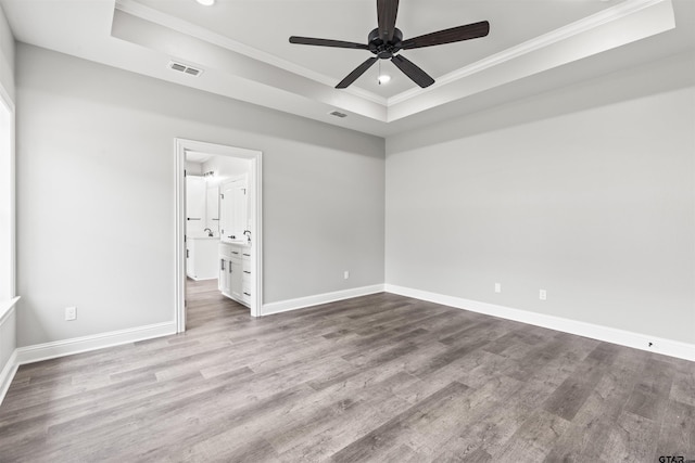 unfurnished room featuring a tray ceiling, ceiling fan, light hardwood / wood-style floors, and ornamental molding