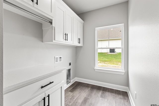 clothes washing area with hookup for an electric dryer, hardwood / wood-style floors, hookup for a washing machine, and cabinets