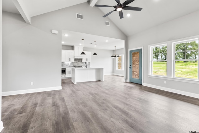 unfurnished living room featuring hardwood / wood-style flooring, ceiling fan with notable chandelier, beam ceiling, and high vaulted ceiling