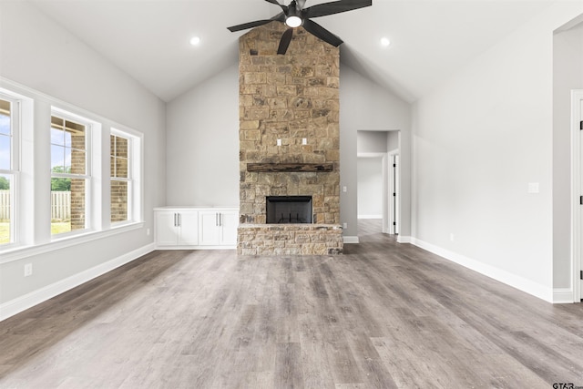 unfurnished living room with high vaulted ceiling, hardwood / wood-style flooring, a stone fireplace, and ceiling fan