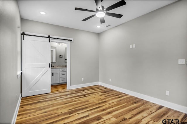 1002 E Main St, Whitehouse, TX 75791 - unfurnished bedroom with a barn door, light wood finished floors, baseboards, ensuite bath, and recessed lighting