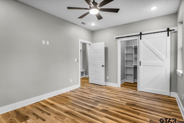 1002 E Main St, Whitehouse, TX 75791 - unfurnished bedroom featuring baseboards, wood finished floors, a barn door, a walk in closet, and recessed lighting
