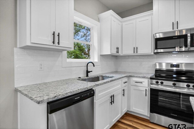 1002 E Main St, Whitehouse, TX 75791 - kitchen featuring appliances with stainless steel finishes, a sink, white cabinets, decorative backsplash, and light stone countertops