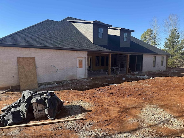 rear view of house featuring a shingled roof, a patio area, and brick siding