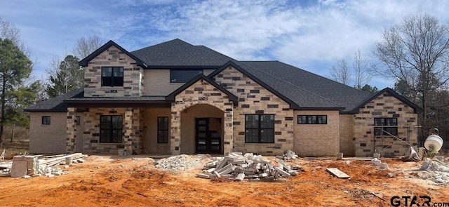 view of front of house with stone siding and roof with shingles