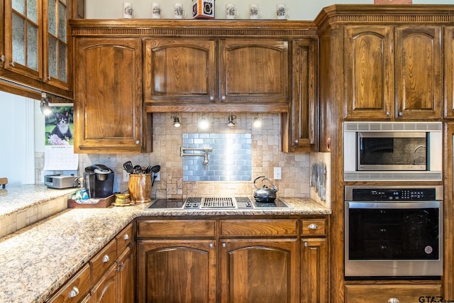 kitchen with tasteful backsplash, light stone countertops, and appliances with stainless steel finishes