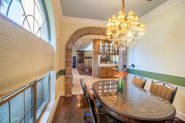 dining space with hardwood / wood-style floors, a chandelier, and crown molding