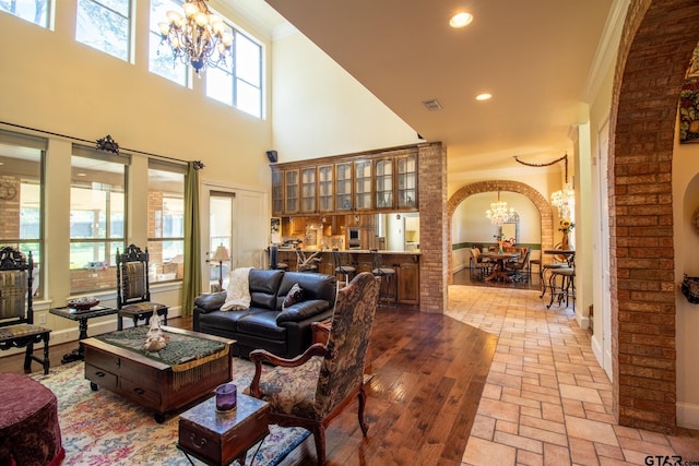 living room featuring a high ceiling, a chandelier, and light hardwood / wood-style flooring