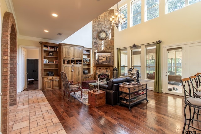 living room with a large fireplace, a towering ceiling, light wood-type flooring, and a notable chandelier