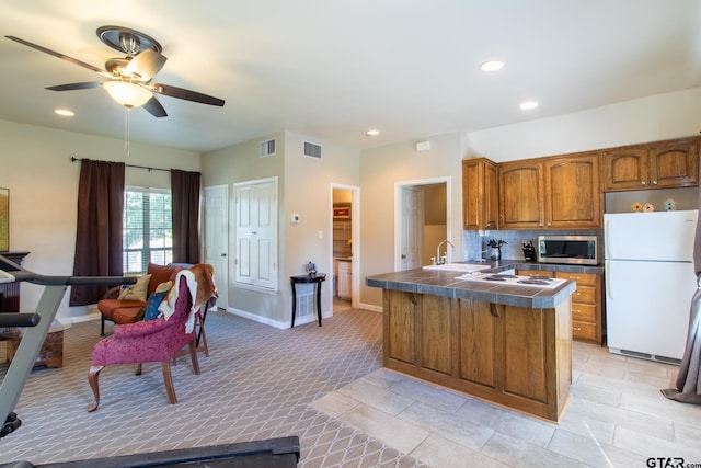 kitchen with kitchen peninsula, sink, ceiling fan, backsplash, and white appliances