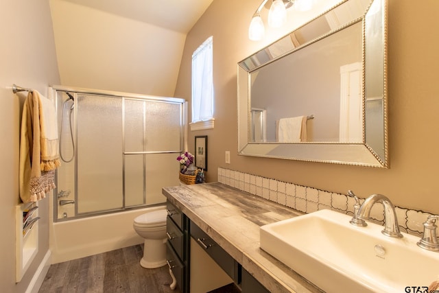 full bathroom featuring vanity, hardwood / wood-style floors, vaulted ceiling, toilet, and combined bath / shower with glass door