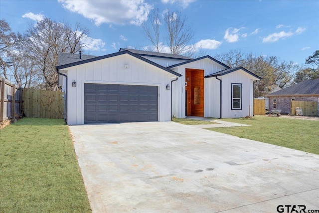 view of front of house featuring an attached garage, concrete driveway, a front lawn, and fence