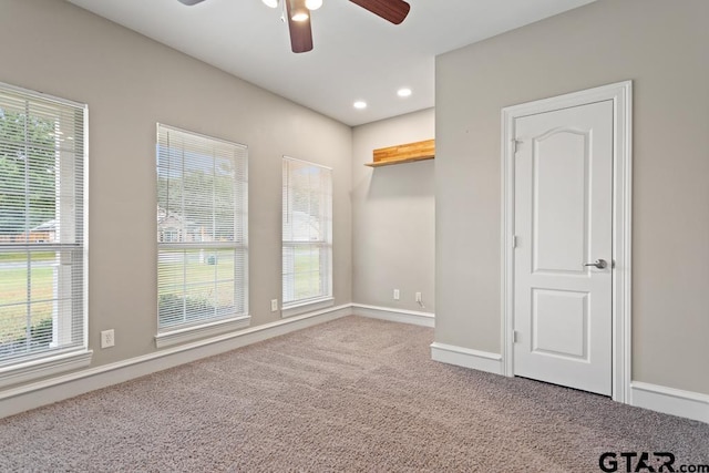 carpeted empty room with a wealth of natural light and ceiling fan