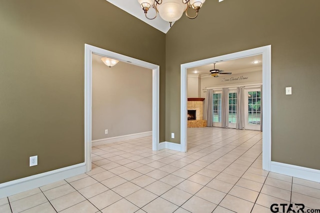 empty room with ceiling fan with notable chandelier, light tile patterned flooring, crown molding, and vaulted ceiling