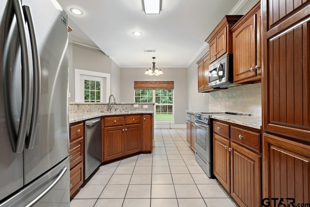 kitchen featuring ornamental molding, an inviting chandelier, hanging light fixtures, and appliances with stainless steel finishes