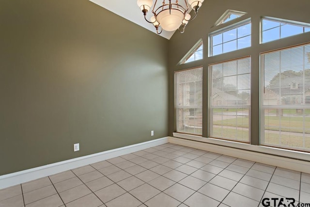 tiled spare room with lofted ceiling and an inviting chandelier