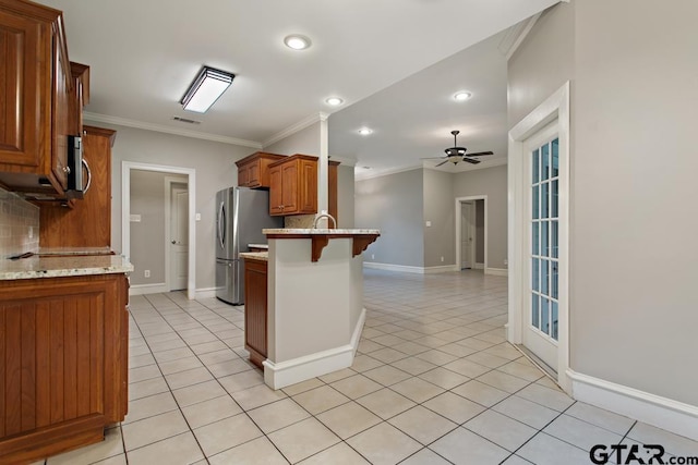 kitchen with ceiling fan, backsplash, a breakfast bar, appliances with stainless steel finishes, and ornamental molding