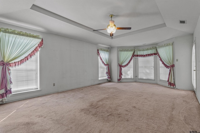 empty room featuring carpet floors, ceiling fan, and a raised ceiling