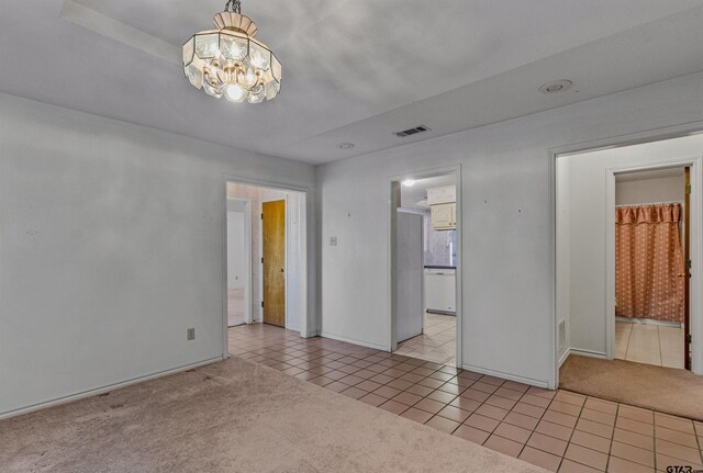 carpeted spare room with a chandelier