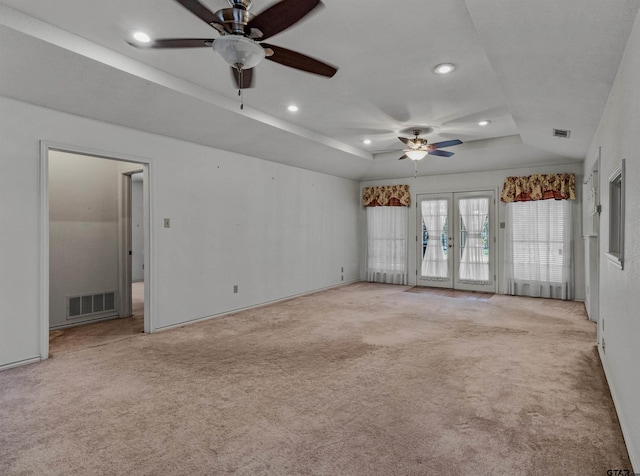 unfurnished room featuring french doors, light colored carpet, ceiling fan, and a tray ceiling