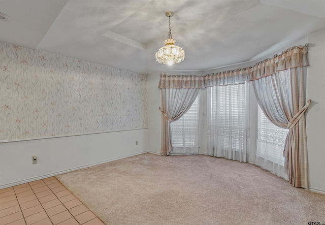 carpeted empty room featuring a notable chandelier