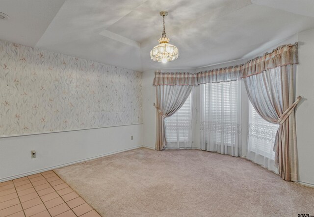 carpeted empty room featuring a notable chandelier