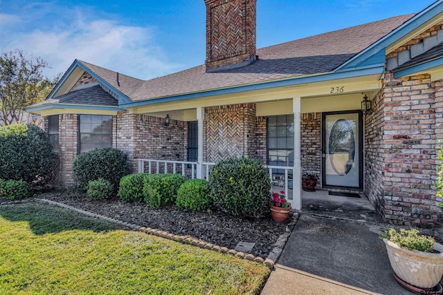 view of exterior entry featuring a yard and covered porch