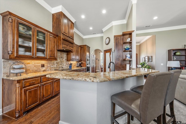 301 Zambezi Ln, Bullard, TX 75757 - kitchen featuring arched walkways, open shelves, a breakfast bar area, light stone counters, and crown molding