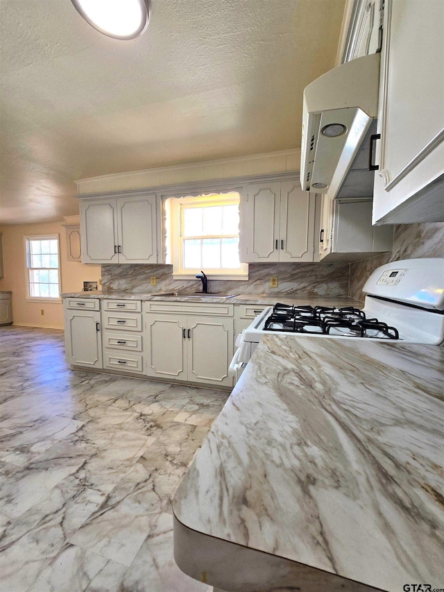 kitchen featuring white range with gas stovetop, a textured ceiling, sink, and exhaust hood