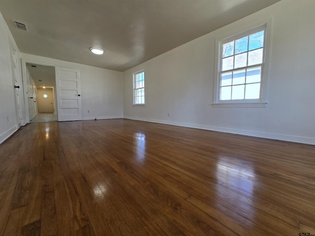 empty room with dark wood-type flooring and a wealth of natural light