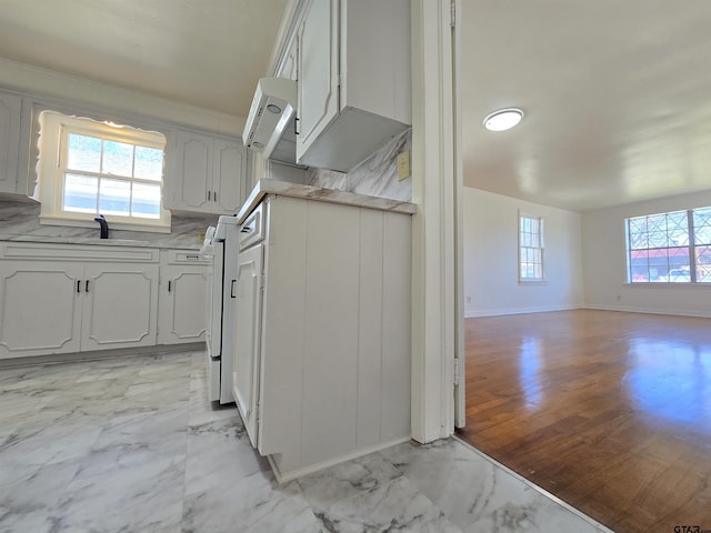 kitchen with sink, backsplash, a healthy amount of sunlight, and white cabinetry