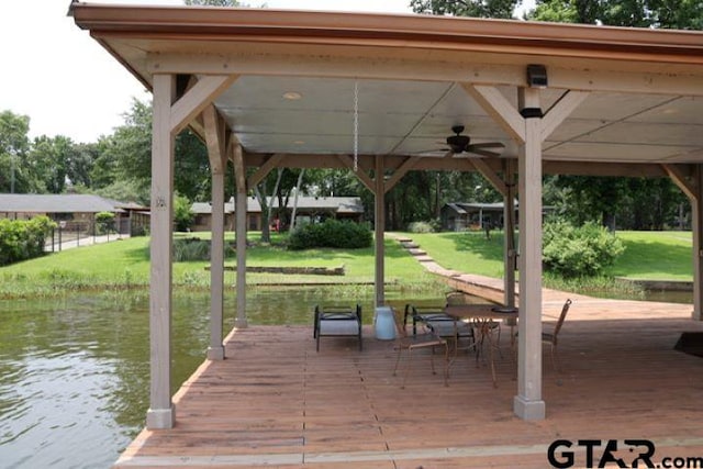 view of dock with a yard and a water view