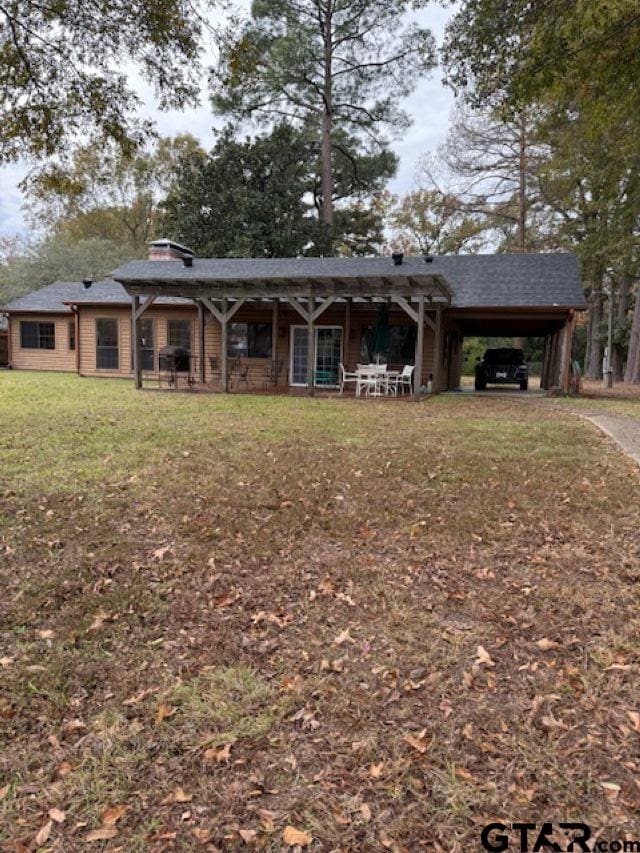 back of house with a carport and a lawn