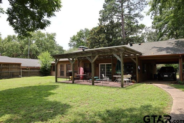 back of house featuring a lawn, a patio, and a carport