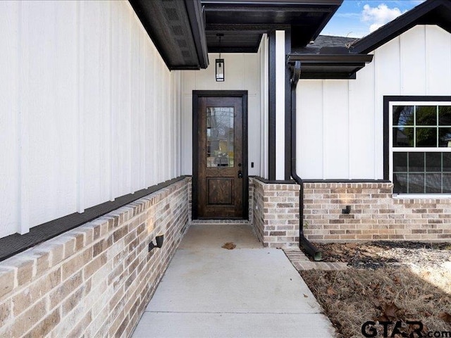 property entrance with board and batten siding and brick siding