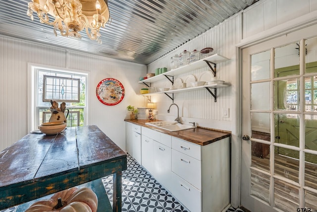 bar with wooden counters, sink, and white cabinets