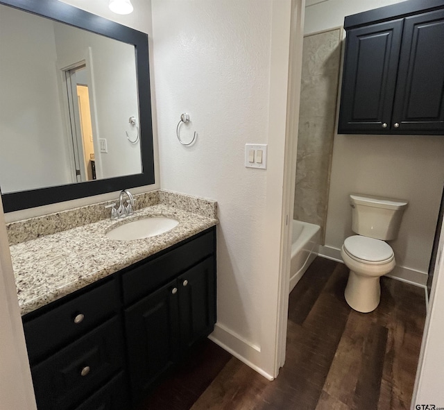 bathroom featuring vanity, baseboards, wood finished floors, and toilet