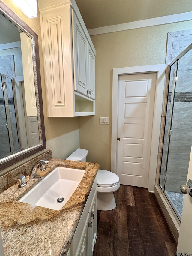 full bath with wood finished floors, a stall shower, toilet, and vanity