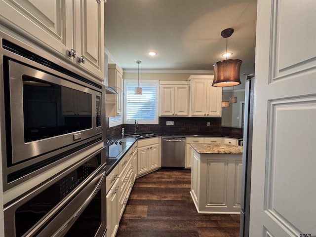 kitchen with decorative backsplash, dark wood-style flooring, a sink, appliances with stainless steel finishes, and decorative light fixtures