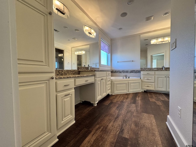 bathroom with a bath, a sink, wood finished floors, and two vanities