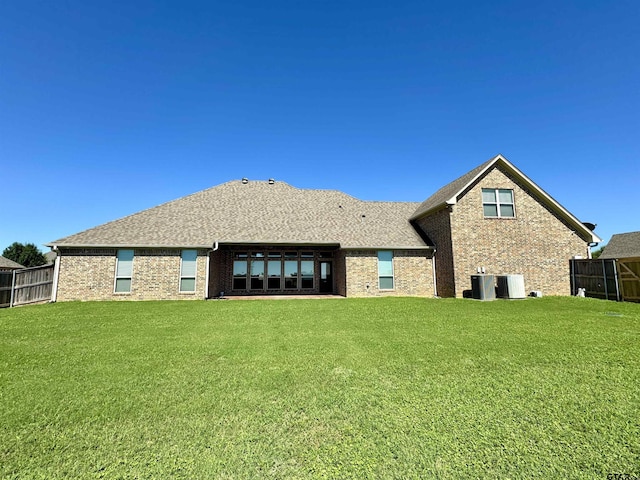 back of property featuring central air condition unit, fence, a lawn, and brick siding