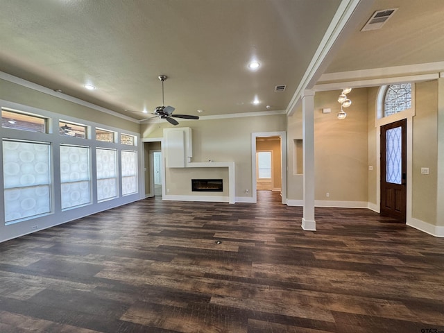 unfurnished living room with crown molding, ceiling fan, dark wood finished floors, baseboards, and visible vents