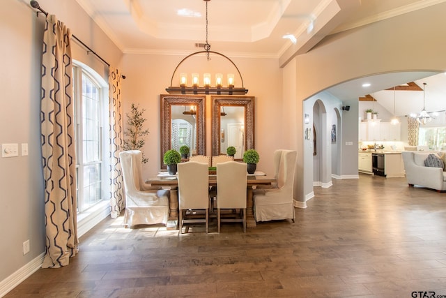 dining room with ornamental molding, a notable chandelier, dark wood-type flooring, and a tray ceiling