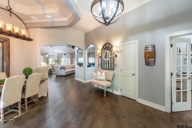 entrance foyer with a notable chandelier, a raised ceiling, dark hardwood / wood-style floors, and crown molding